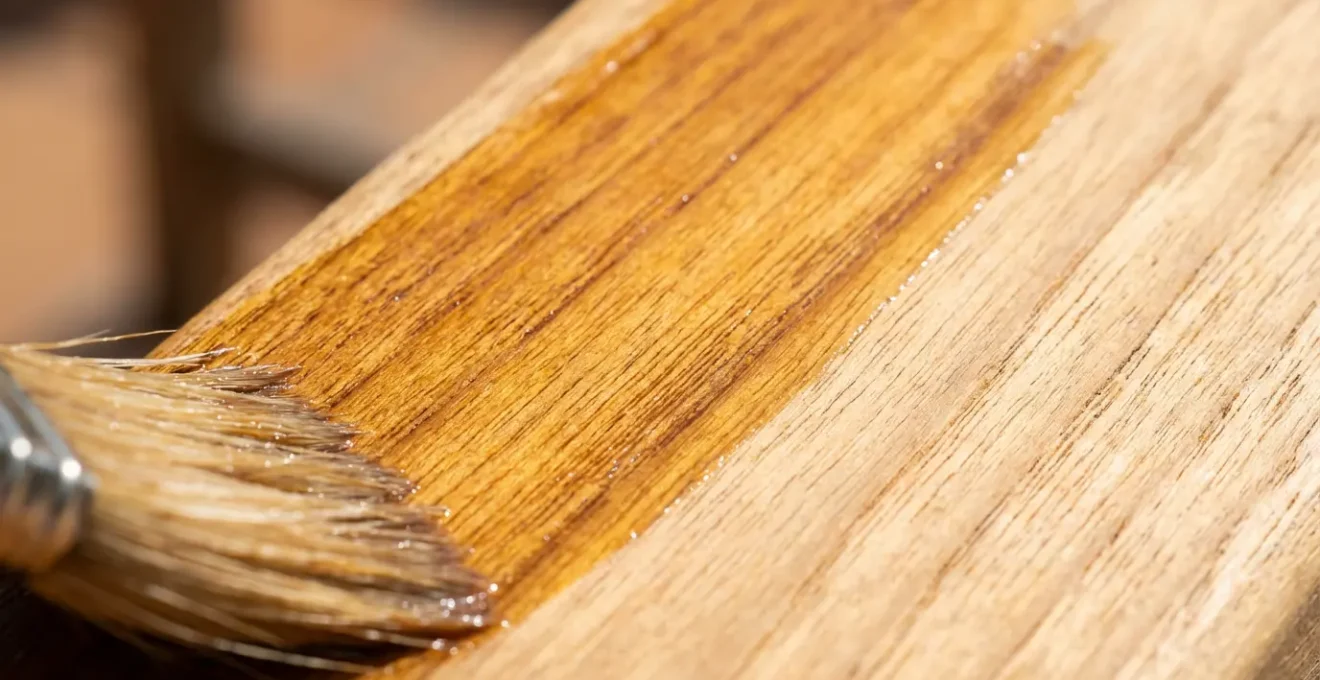 Application d'un saturateur sur une terrasse en teck avec pinceau large