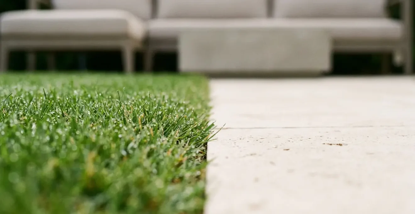Jardin minimaliste avec une pelouse parfaitement verte, des haies taillées et une terrasse en pierre naturelle, exemple de neutralité valorisante.
